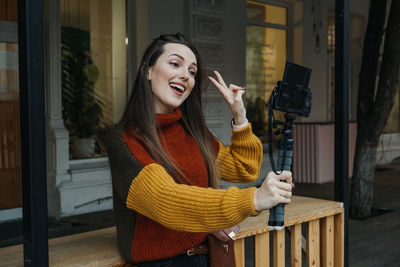 Young woman smiling while standing against wall