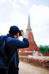 Man photographing stupa against sky