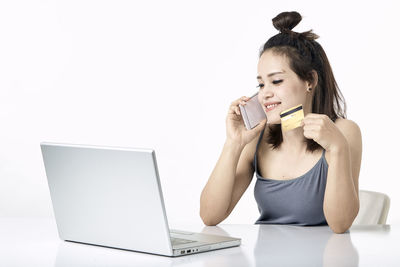 Young woman using mobile phone while sitting on table