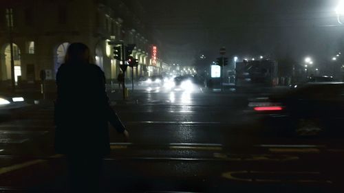 Rear view of woman walking in illuminated city