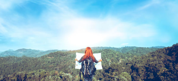 Rear view of woman standing on mountain against sky