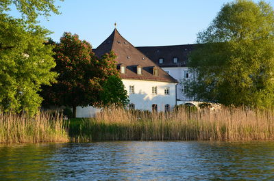 Houses by lake against clear sky