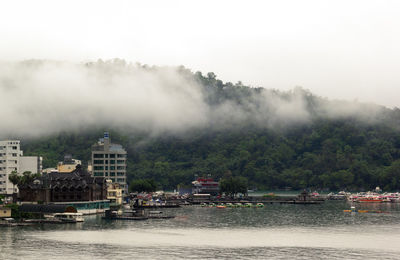 Scenic view of waterfront at sun moon lake with fog covering mountain