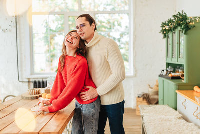Young man and woman romantic couple couple hug at the kitchen while coocking and backing