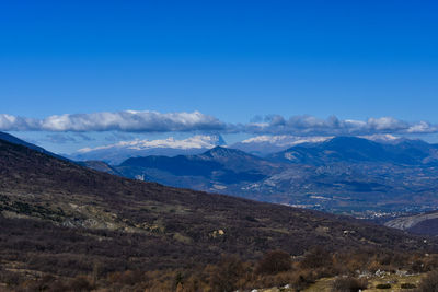 Scenic view of snowcapped mountains against blue sky