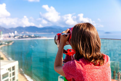 Rear view of woman looking at sea against sky