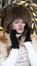 Portrait of beautiful woman wearing fur coat and hat siting outdoors