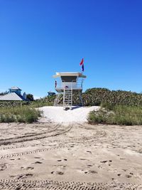 Lifeguard hut against clear blue sky at beach