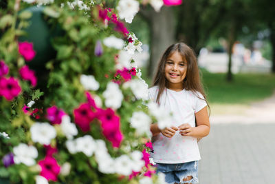 Beautiful little girl with long hair in bright colors in summer in the park
