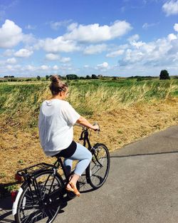 Man riding bicycle on road against sky