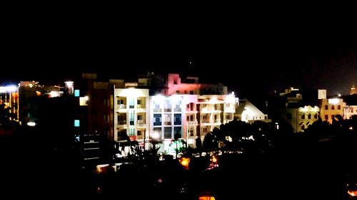 Illuminated cityscape against sky at night