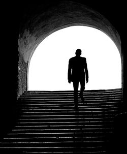 Rear view of silhouette man standing in tunnel