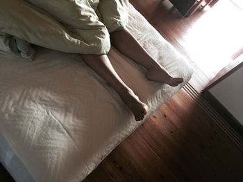 Low section of person relaxing on bed at home