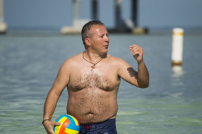 Full length of shirtless man standing in sea