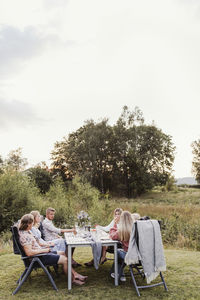 Group of people sitting on table against trees