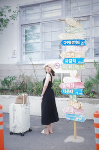 Rear view of young woman standing against wall