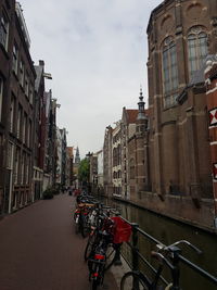 Bicycles parked on road by canal against buildings in city