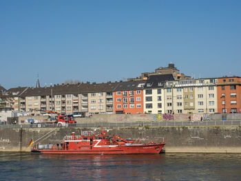 Buildings by sea against clear blue sky