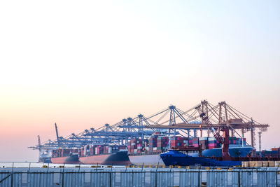 Cranes at commercial dock against clear sky