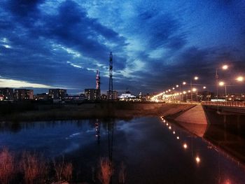 Illuminated city against cloudy sky at dusk