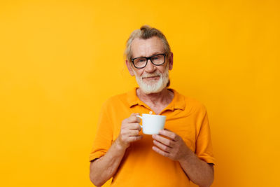 Young woman using mobile phone against yellow background