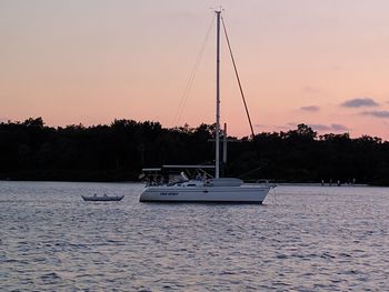 Sailboat sailing on sea against clear sky during sunset