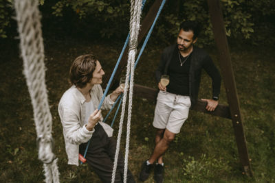 Rear view of two men on swing at playground