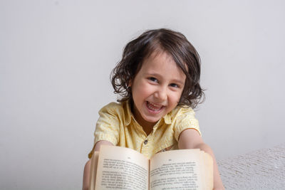 Portrait of a smiling girl holding book against white background