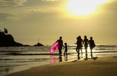 People on beach against sky during sunset