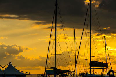 Sailboats moored in sea against sky during sunset