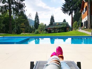 Low section of person standing by swimming pool against trees