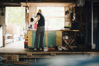 Full length rear view of woman washing dishes at summer house