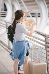 Rear view of woman holding umbrella while standing in bus