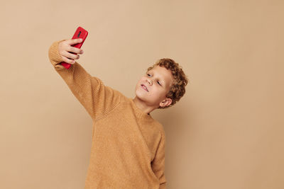 Boy taking selfie against beige background