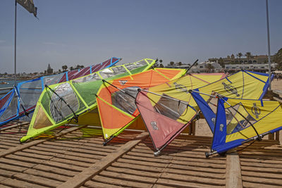 Multi colored umbrellas hanging against boats against clear sky