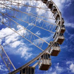 Low angle view of ferris wheel against cloudy sky