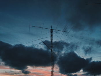 Low angle view of electricity pylon against sky during sunset