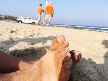 Low section of woman on beach against sky