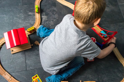 High angle view of boy playing with miniature train at home