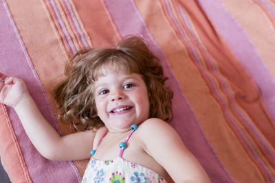 Portrait of smiling cute girl lying on sofa