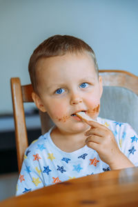 Little cute boy eating bread with chocolate butter