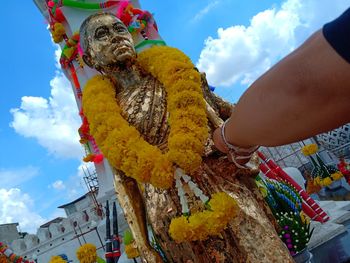 Cropped hand touching statue in temple