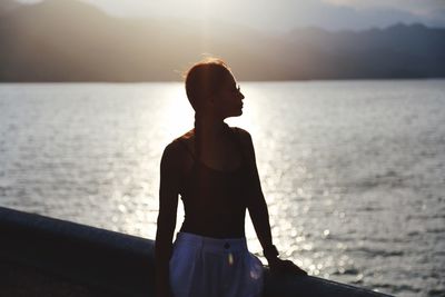 Woman standing against sea during sunset