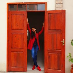 Portrait of woman standing against door