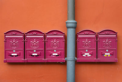 Close-up of pipe and mailboxes on orange wall