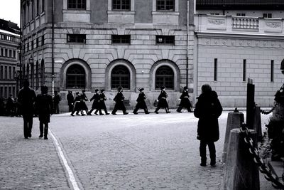 Honor guard marching on parade by historic building in city