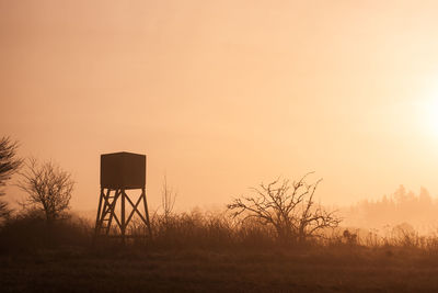 Lookout tower on field against clear sky during sunrise