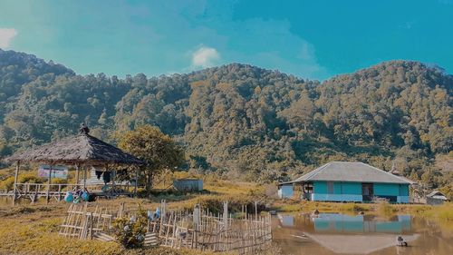 Houses by trees and mountains against sky