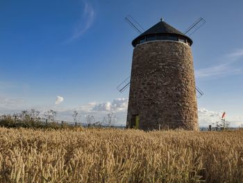 Traditional windmill on field against sky