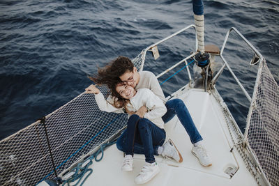 High angle view of friends sitting on railing against sea